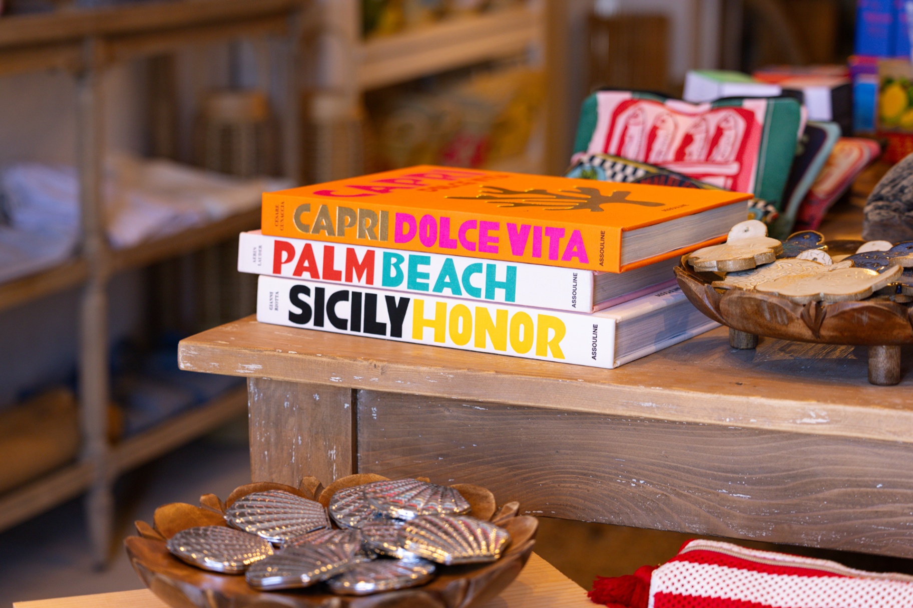 Coffee table books — Capri Dolce Vita, Palm Beach, Sicily — stacked on a wooden bench at Le Shack Beach